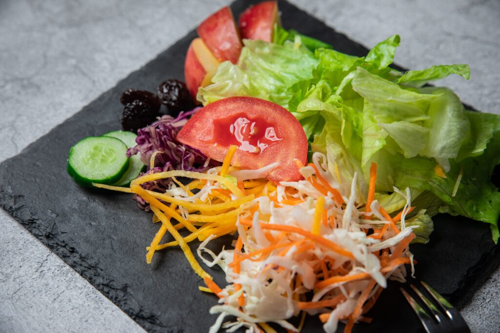 Vibrant mixed vegetable salad with lettuce, tomatoes, and cucumbers served on a slate plate.