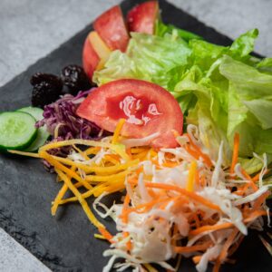 Vibrant mixed vegetable salad with lettuce, tomatoes, and cucumbers served on a slate plate.