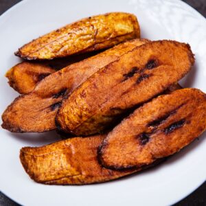 Close-up of crispy fried plantains served on a white plate. Mouth-watering and tasty.