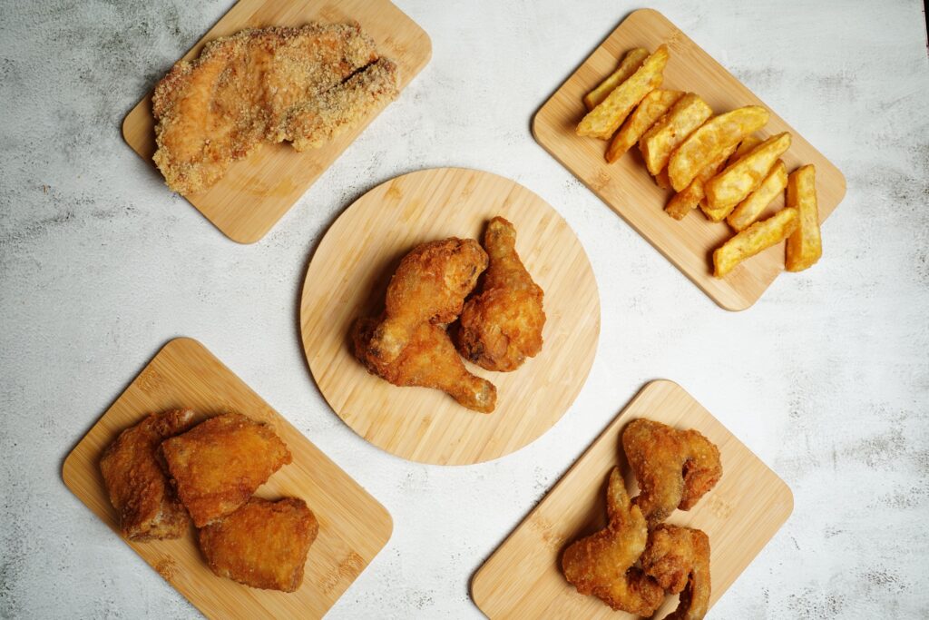 Top view of delicious crispy fried chicken and golden fries on wooden trays for a perfect meal.