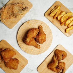 Top view of delicious crispy fried chicken and golden fries on wooden trays for a perfect meal.